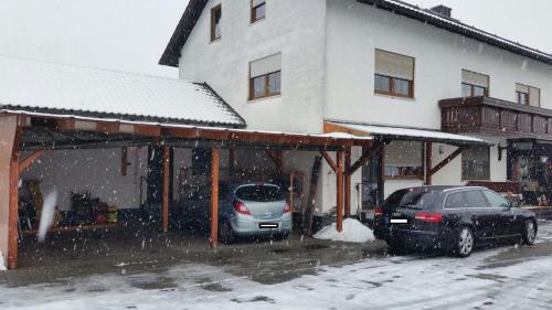 zwei Autos, die vor einem Gebäude im Schnee geparkt sind in der Unterkunft Haus Eva in Eslarn