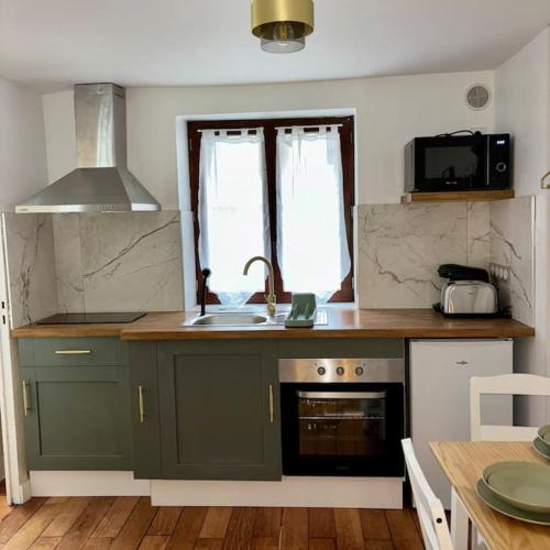 une cuisine avec des armoires vertes et un évier dans l'établissement Le Living Roissy CDG, à Longperrier