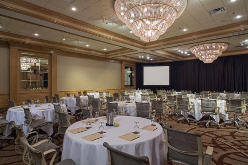 a banquet hall with white tables and chairs and a screen at The San Luis Resort Spa & Conference Center in Galveston