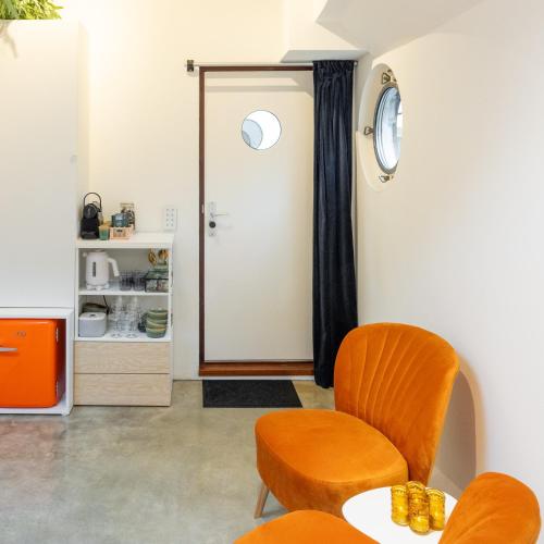 a room with two chairs and a table and a door at Boat suite - A Unique Houseboat Stay in Amsterdam in Amsterdam