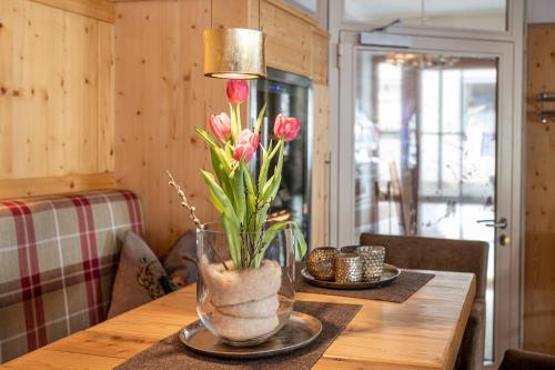 a vase with pink flowers on a wooden table at Hotel Tauernblick in Obertauern