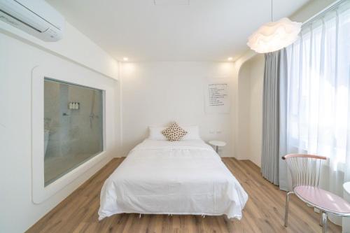 a white bedroom with a bed and a window at Nantuju in Ch'ih-k'an-lou