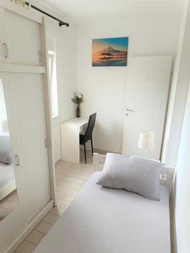 a white bedroom with a bed and a desk at Apartment Mario, Novalja in Novalja