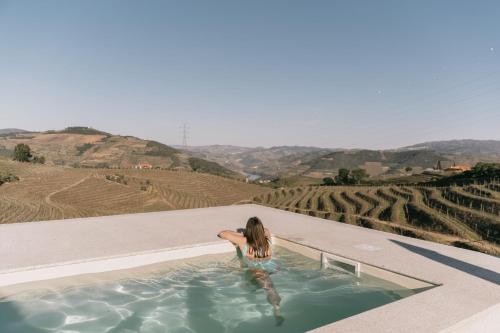 a woman in a hot tub overlooking a vineyard at Feel Discovery Quinta do Muro Douro Valley in Peso da Régua