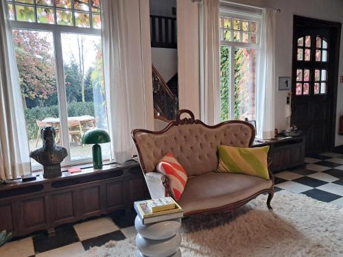 a living room with a couch in a room with windows at Het Bed van den Doktoor in Meerhout
