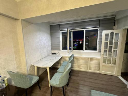 una stanza con un tavolo, delle sedie e una finestra di Anisa Apartment a Tashkent