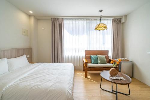 a bedroom with a bed and a chair and a table at Nantuju in Ch'ih-k'an-lou
