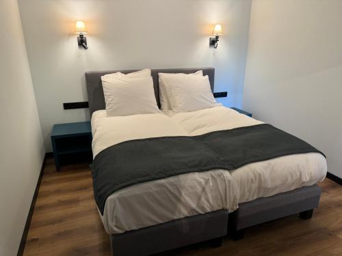 a large bed in a room with two lights at Longstay Achterhoek in Zeddam
