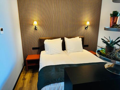 a hotel room with a bed with white sheets and pillows at Longstay Achterhoek in Zeddam