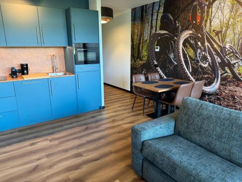a kitchen with blue cabinets and a table and a couch at Longstay Achterhoek in Zeddam