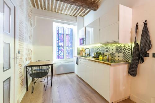 une cuisine avec des armoires blanches, une table et une fenêtre dans l'établissement T1 pop tout neuf au Panier, à Marseille