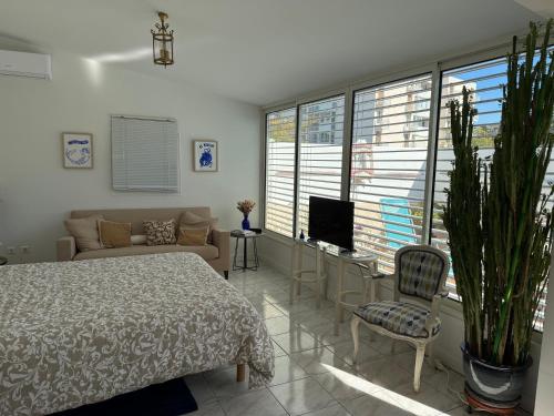 une chambre avec un lit, un canapé et une télévision dans l'établissement L'OASIS BLEUE spa et terrasse, à Sète