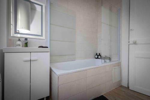 un bagno bianco con vasca e lavandino di Évasion Zen Tropic au Cœur de Châteaudun a Châteaudun