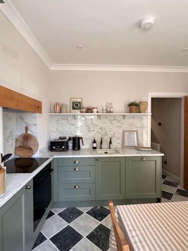 a kitchen with green cabinets and a checkered floor at Charming Townhouse Retreat in Shrewsbury