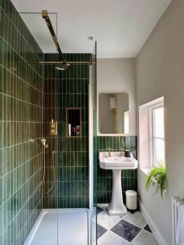 baño de azulejos verdes con lavabo y ducha en Charming Townhouse Retreat, en Shrewsbury