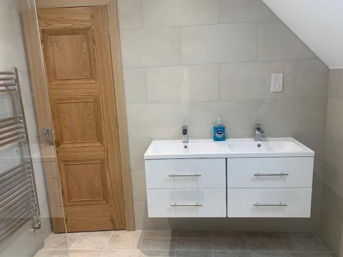 a bathroom with a white sink and a wooden door at A space with amazing views and alpacas to enjoy in Chewton Mendip