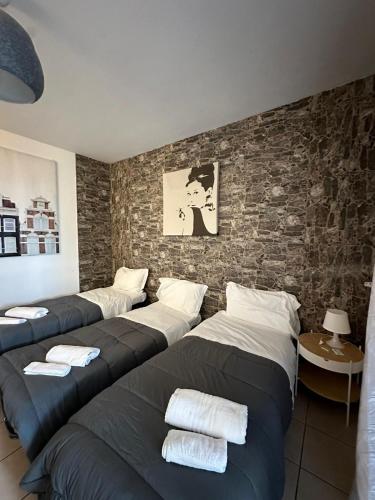a room with four beds and a brick wall at Affittacamere Karma Rho-Fiera in Rho