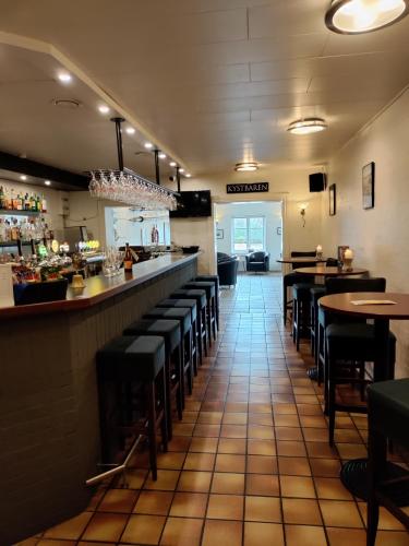a restaurant with a bar with black stools at Rønnes Hotel in Fjerritslev