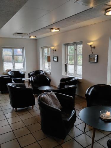 a waiting room with chairs and tables and windows at Rønnes Hotel in Fjerritslev