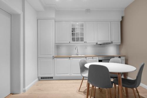 a kitchen with white cabinets and a table and chairs at Leilighet midt i sentrum in Tromsø