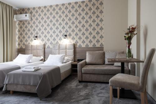 a hotel room with two beds and a chair at Hotel Maksymilian in Krakow