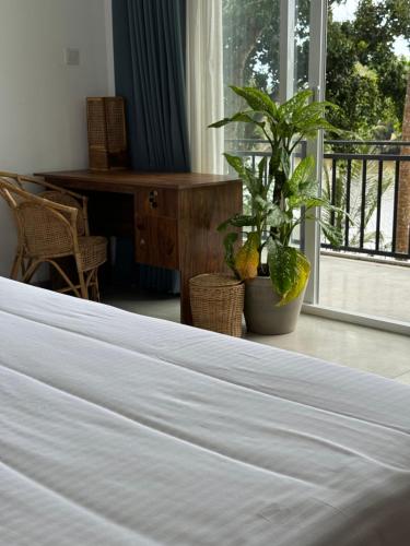 a white bed in a room with a plant at Sapiens home - Weligama bay in Weligama