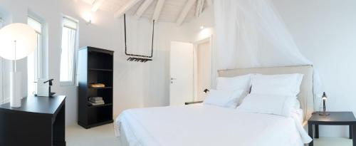 a white bedroom with a white bed and a black table at Shangri-La in Meganisi