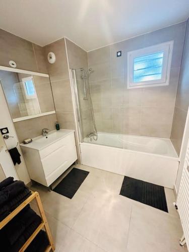 une salle de bain blanche avec une baignoire et un lavabo dans l'établissement Cosy flat with garden, close to Paris and metro station, à Romainville
