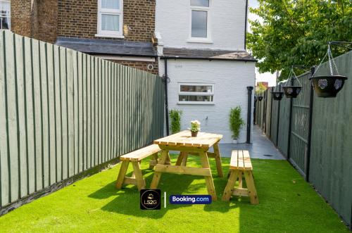 a wooden picnic table and two chairs in a backyard at Spacious 5-Bed House with Parking in Wood Green by LS2G Stays in London