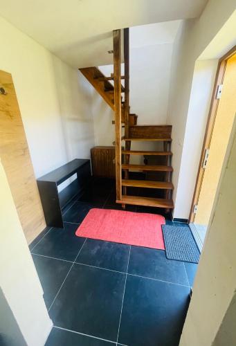 an attic room with a red rug and stairs at Apartmán Zara in Dobrá Voda