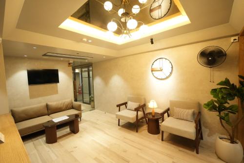 a living room with a couch and chairs and a clock at SIVANTA by BOMBAY GROUP OF HOTELS NAGPUR in Nagpur