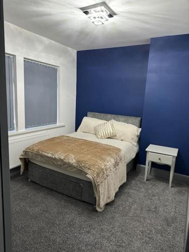 a blue bedroom with a bed and a blue wall at Nice house with free Parking in Newcastle upon Tyne