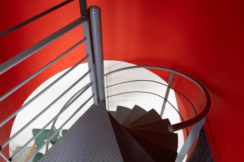 a staircase with a red wall and a metal rail at ResArt Traditional House in Nicosia