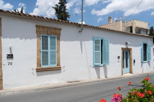 a white building with blue shutters on a street at ResArt Traditional House in Nicosia