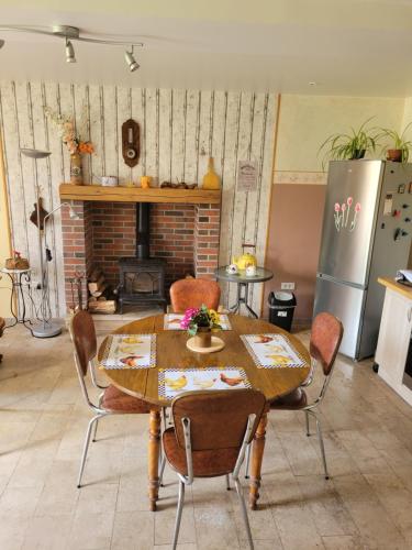 une cuisine avec une table et des chaises ainsi qu'une cheminée dans l'établissement La Ptite Maison de Campagne, à Ancy-le-Libre
