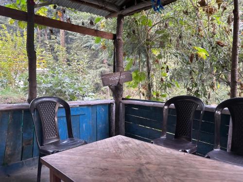 a wooden table and four chairs on a porch at Happy Returns Home, Jibhi in Jibhi