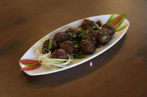 a plate of meatballs and vegetables on a table at SIVANTA by BOMBAY GROUP OF HOTELS NAGPUR in Nagpur