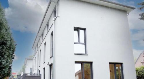 a white house with black windows on a street at Exklusives Haus Grenze Hamburg West in Hamburg
