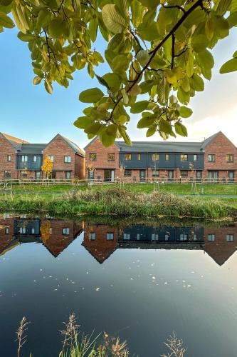 a building next to a body of water at Newbuild Riverview 3BDR House near Glasgow in Dalmuir