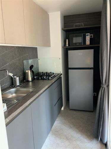 a kitchen with a sink and a refrigerator at Victoria Mobilehome BI VILLAGE in Fažana