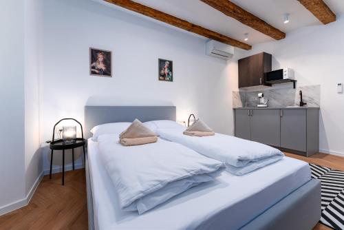a bedroom with two white beds and a kitchen at Corso Apartments in Rijeka