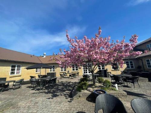 a tree with pink flowers in front of a building at Rønnes Hotel in Fjerritslev