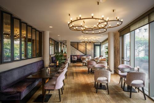 een restaurant met tafels en stoelen en een kroonluchter bij Monet Garden Hotel Amsterdam in Amsterdam