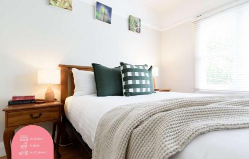 a bedroom with a bed with green and white pillows at The Basin Cottage in Royal Park