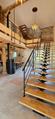 a staircase in a living room with wooden stairs at Chambre d'hôte de charme L'Escapada Les Échappées Belles in Antignac