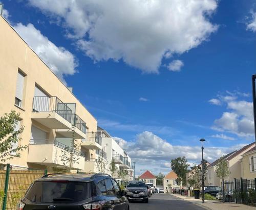 une rue avec des voitures garées devant les bâtiments dans l'établissement T2 Neuf, proche Paris & Disneyland, à Ozoir-la-Ferrière