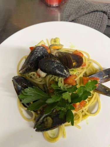 a plate of pasta with mussels and vegetables on it at Albergo Ristorante Plaza in Tornolo