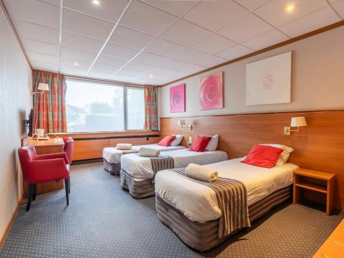 a hotel room with three beds and a chair at Sleep & Go Menen in Menen