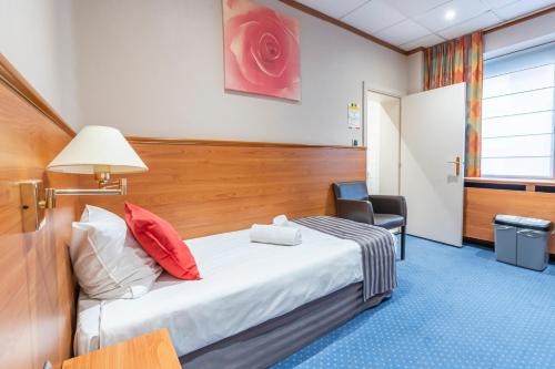 a hotel room with a bed and a chair at Sleep & Go Menen in Menen