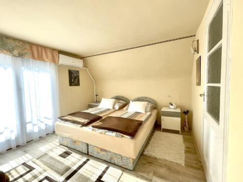 a bedroom with a bed and a large window at Heilmann Ház in Harkány